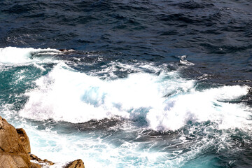 Powerful ocean waves crashing against rocky shore creating dynamic white foam and deep blue contrast