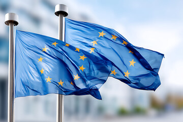 Two Waving European Union Flags Against A Blurry Background Under A Bright Blue Sky