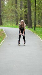 Attractive blonde feels free and light while rollerblading in city park in summer. Stunning Caucasian woman with beautiful figure uses roller skates for outdoor sports.