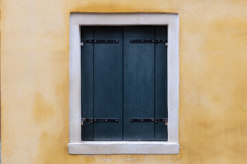 Closed Dark Shutters on Yellow Wall
