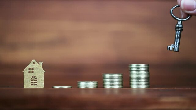 Hand puts a key next to house and gold money coins. Financial solution, home buying concept.