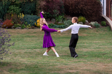 Elegant young boy and girl in ballroom dance attire performing outdoors. This juvenile dance couple captures grace, discipline, and youthful passion in a natural, outdoor setting. Ideal for themes rel