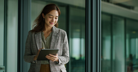 Focused Young women Professional Writing on iPad in Modern Glass-Walled Office