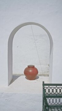 Woman walking past whitewashed arch with a large clay pot in haria lanzarote canary islands outdoors