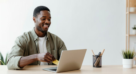 African male adult using laptop for online shopping in minimalist workspace
