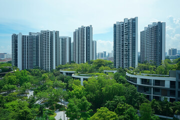 Naklejka premium city skyline with a large green park in the middle. The park is surrounded by tall buildings, including a large apartment complex. The sky is clear and the sun is shining, creating a bright