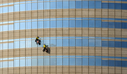 high rise building Window washers cleaning the glass facade of a modern building, skyscraper high risk work.