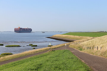 a beautiful coast landscape in zeeland with a big container ship in the westerschelde sea and a...