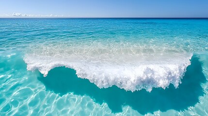 Ocean Wave Breaking on Turquoise Water Under a Clear Blue Sky