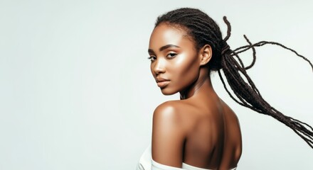 Fototapeta premium Elegant young african female with dreadlocks and radiant skin in off-shoulder pose
