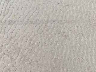 Close-up image showing the texture of sand on the beach, highlighting the wavy marks left by movements and footprints.