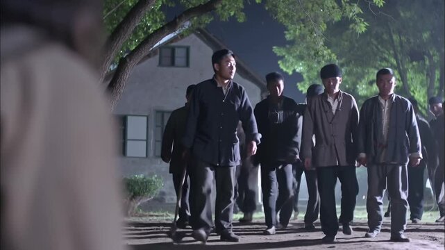 Groupe d'hommes armés de bâtons marchant la nuit vers une confrontation