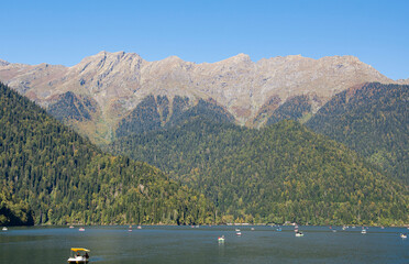Gaga district, Abkhazia October 12, 2024: Alpine lake Ritsa. Boats sail on smooth turquoise water....