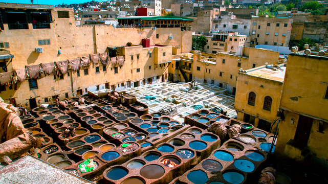 View of the famous tanneries of Fez, with colorful dye pits, sun-drying hides, and artisans working in the heart of the medina.