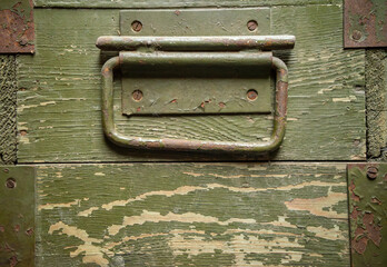 Military wooden shell box background.An old wooden door with green paint and rusty metal elements