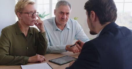 Consultant, agent or adviser conducts a professional meeting with a pair of senior clients in an office. They discuss financial, insurance, or real estate matters in a collaborative setting.