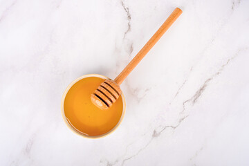 Top view of fresh honey in white saucer with wooden honey spoon.