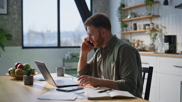 Busy freelancer answering call working laptop in home office closeup. Happy man