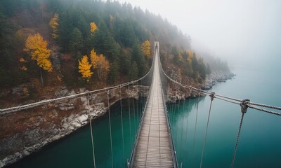 Obraz premium Misty Mountain Suspension Bridge Spanning Teal Waters