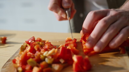 Chef hands slicing pepper on board kitchen closeup. Man chopping vegetables