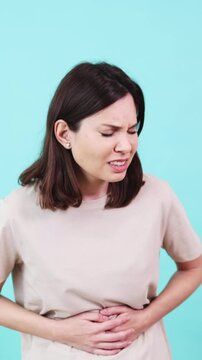Woman suffering from abdominal pain on turquoise background