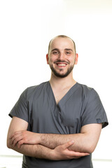 Fototapeta premium Smiling Male Medical Professional in Scrubs Posing with Confident Posture and Friendly Expression in Bright, Minimalist Environment