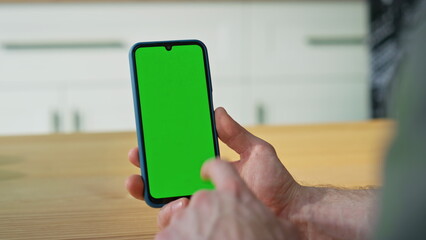 Man scrolling chroma key mobile phone making online purchases at home closeup.