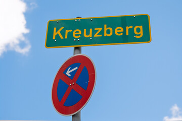 Ortsschild Kreuzberg mit Halteverbotsschild vor blauem Himmel in Berlin, Deutschland