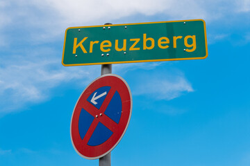 Ortsschild Kreuzberg mit Halteverbotsschild vor blauem Himmel in Berlin, Deutschland