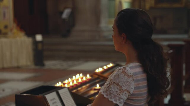 Female tourist or worshiper is praying and looking at chapel altar inside church. Young woman visiting ancient old cathedral in Italy Europe is taking peaceful moment to herself wishing or sightseeing
