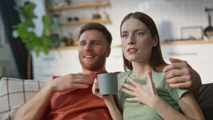 Emotional couple watching serial at home sofa closeup. Married woman and man