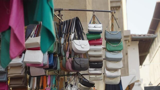 Italian fashion leather accessories purses and handbags in street market. Shopping for designer handmade bags. Leather goods and chic clothes in boutique stand selling local artisanal craft products