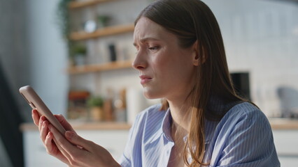 Unhappy woman finish call by mobile phone in home closeup. Sorrowful young lady