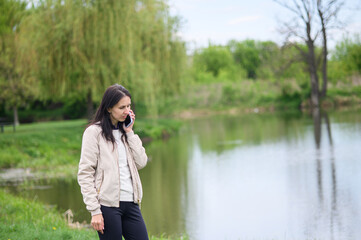 Smiling woman making a video call in park and pointing upward