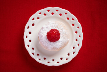 Top view of a small free gluten mini cake with sugar glass and a fresh raspberry on top. It is on a small wicker tray. fresh, baked and handmade. The dish is placed on a red table