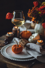 Atmospheric autumn elegant beautiful table setting with pumpkins for a wedding or thanksgiving family celebration. Fall decoration countryside rustic style, cozy home atmosphere , candles, wine