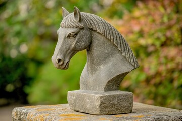 Gray stone horse head bust resting on a stone pedestal.