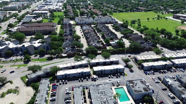 Apartment complex with flat bitumen roof system in midtown Dallas, large rental units community with swimming pool, children playground, uncovered parking near Marcus Park, Josey Ln, flyover