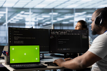 Isolated screen laptop next to man coding in server farm while listening music in headphones....