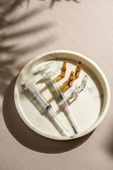  syringes, ampoules, top view, medical gloves, disposable cap arranged on a light background, natural sunlight. medical preparation or cosmetic procedure setup