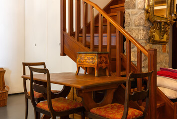 Table and chairs at the base of a wooden staircase in a classical style furnished apartment interior