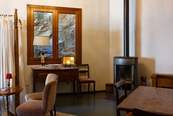 Open-space interior finely decorated with classical-style furniture, with a desk and a wood stove