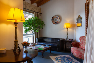 Living room finely decorated with classical-style furniture, with a black leather sofa, a red armchair and two lamps