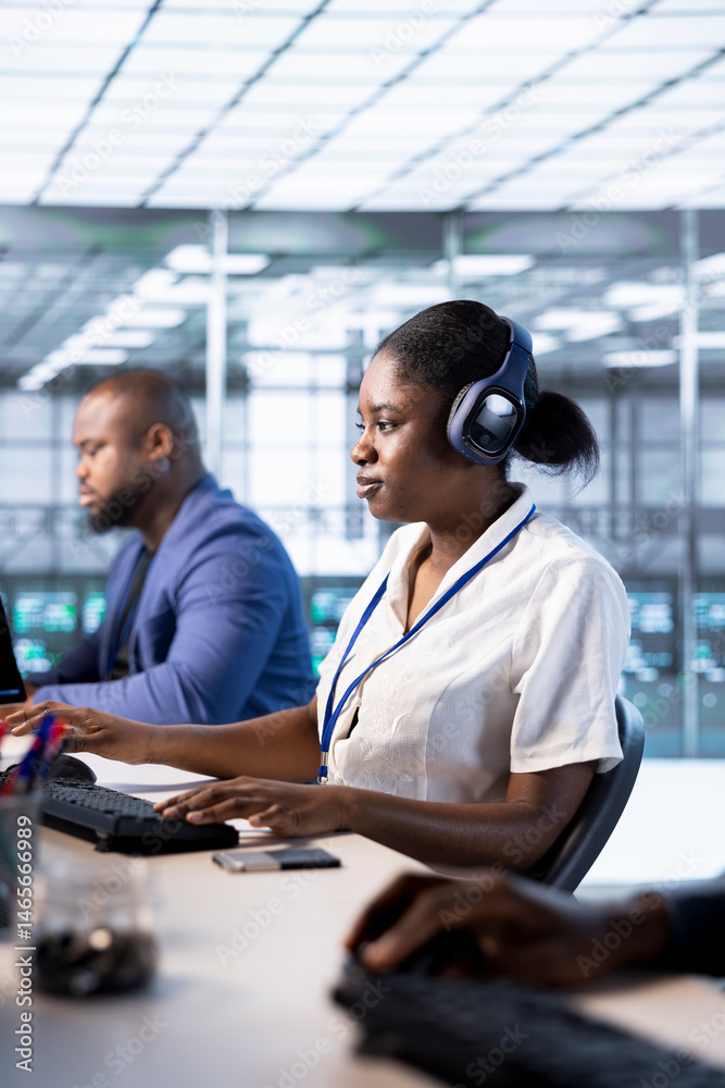 Poster woman in data center wearing headphones, running system diagnostic tests on pc. worker listening mus