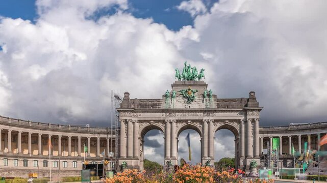 Timelapse of the Cinquantenaire Arcade in Jubelpark, Brussels, Belgium. The memorial triumphal arch with flowerbed stands tall under dramatic clouds, symbolizing Belgian history and independence.