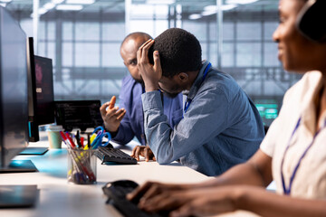 Technician doing face palm gesture, failing to optimize server farm for data processing requirements of customers. Upset man in data center struggling to make equipment operate efficiently