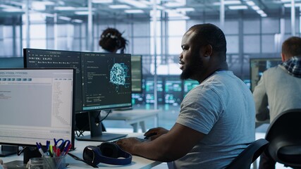 Engineer writing code and doing checkup on server room providing computing resources for different...