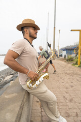 Saxophonist playing sax on beach, seeking inspiration