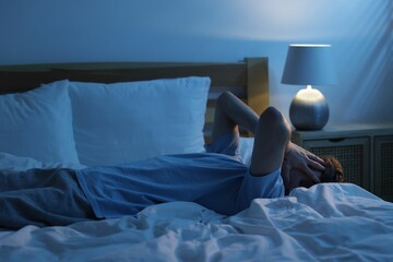 Frustrated man suffering from insomnia on bed indoors