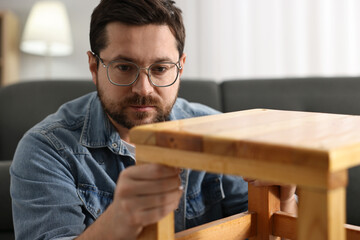 Man repairing wooden stool at home, selective focus